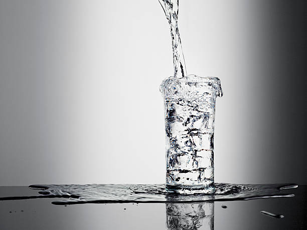 Water pouring into glass and overflowing  glass of water stock pictures, royalty-free photos & images