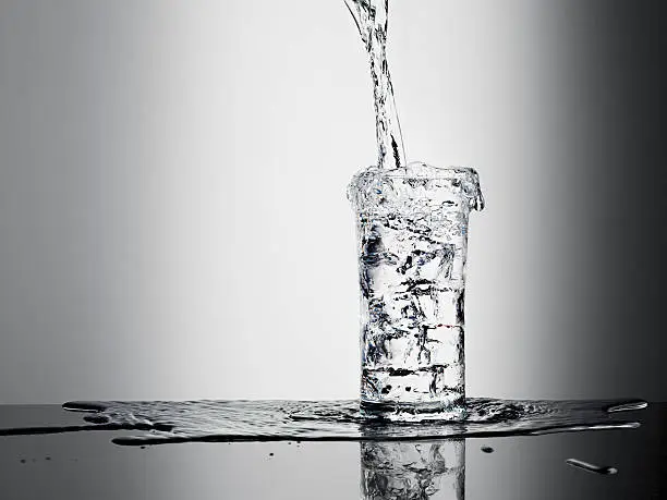 Photo of Water pouring into glass and overflowing