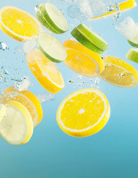 Close up of sliced lemons and limes splashing in water  lime photos stock pictures, royalty-free photos & images
