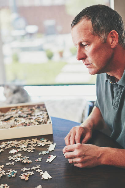 istock Mature man at home working on jigsaw puzzle 979729790