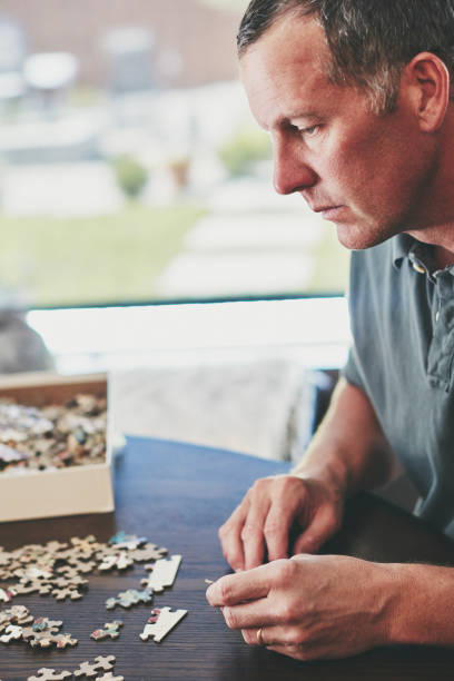 istock Mature man at home working on jigsaw puzzle 979729794