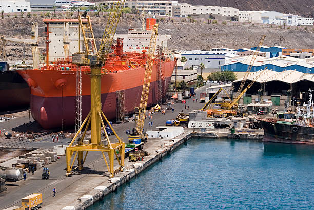 Large orange and red container ship being worked on in dock