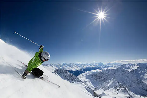 Photo of Skier with sun and mountains