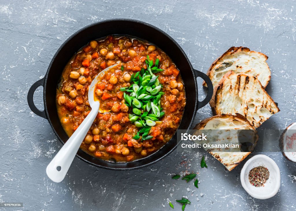 Vegetarian mushrooms chickpea stew in a iron pan and rustic grilled bread on a gray background, top view. Healthy vegetarian food concept. Vegetarian chili Chick-Pea Stock Photo