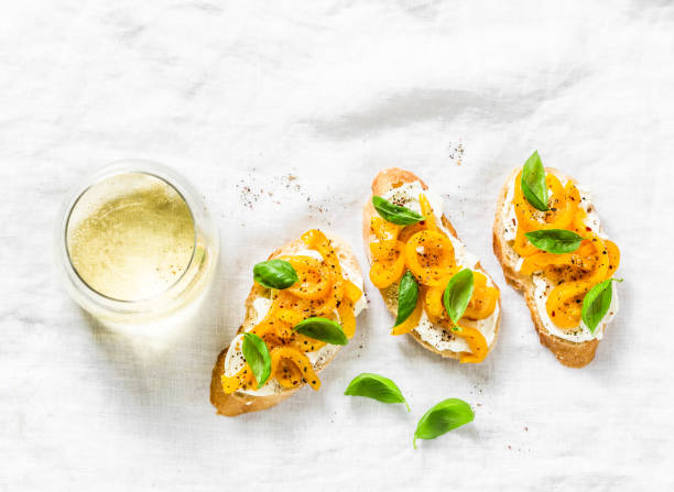 creme de queijo, pimentão amarelo assado, bruschetta de manjericão e vinho branco na luz de fundo, a vista superior. postura plana, cópia espaço - antipasto roasted pepper bell pepper pepper - fotografias e filmes do acervo