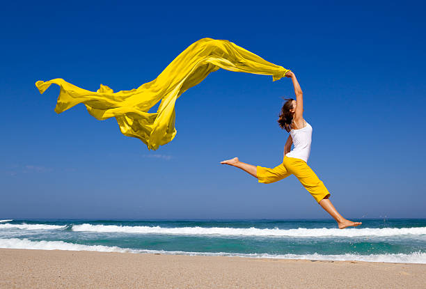 istock Young woman jumping on beach with orange tissue 97980721