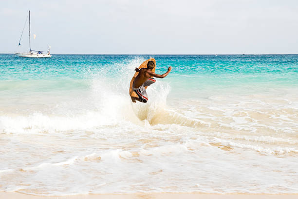 若い男ジャンプ波にサテンスキマーボード - skimboard ストックフォトと画像