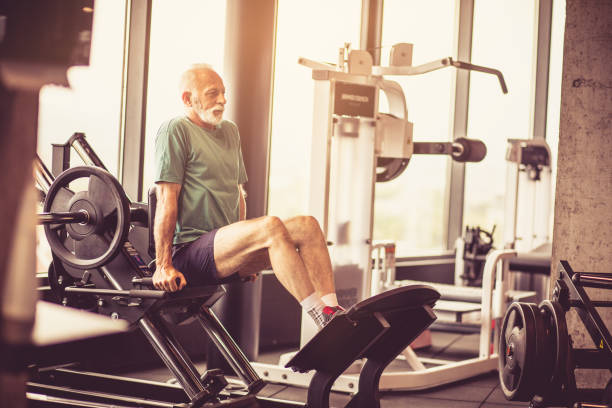 Exercise on machine for legs. Senior man working exercise on machine for legs. senior bodybuilders stock pictures, royalty-free photos & images