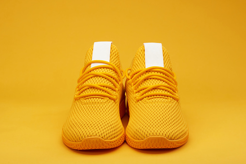 Front view of sport yellow  pair shoes on orange background