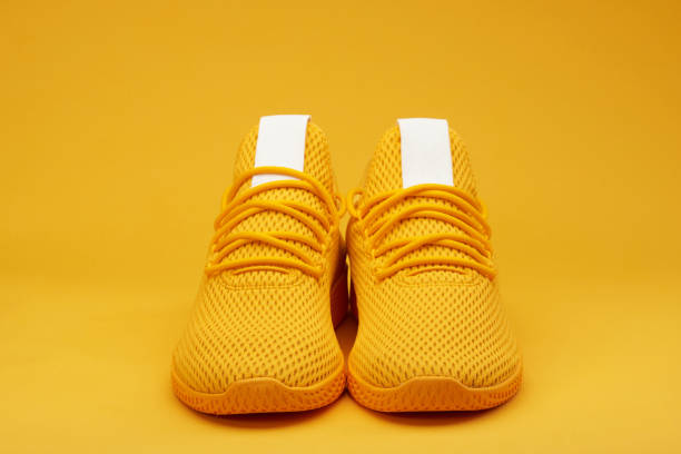 Front view of sport yellow  pair shoes Front view of sport yellow  pair shoes on orange background yellow shoes stock pictures, royalty-free photos & images