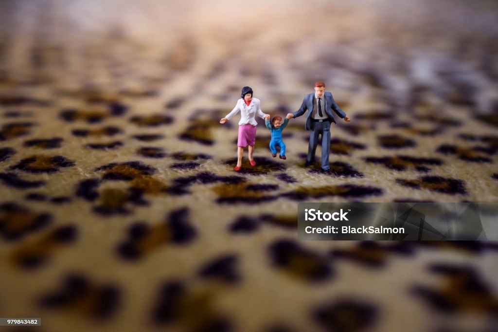 Happy Family Concept. present by Miniature Figure of Father, Mother and Son with Happiness Moment. Walking on Tiger Printed  Fabric Figurine Stock Photo