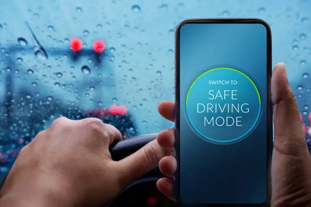 Drive with Safe Concept. Driver Switching Smartphone to Safety Mode. Rainy Day and Bad Weather on the Road with Blurred Lights and Traffic Jam in City
