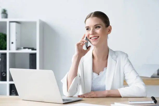 happyyoung businesswoman talking by phone at office