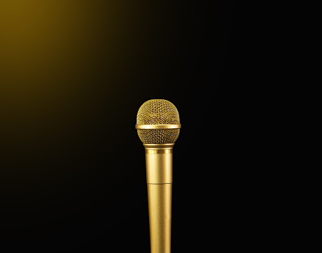 Golden microphone with sport light on black background.