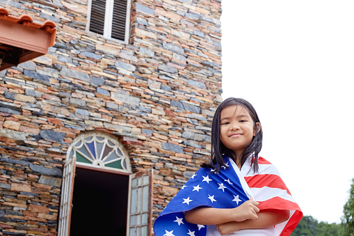 Cute little asian girl with USA flag in backyard home