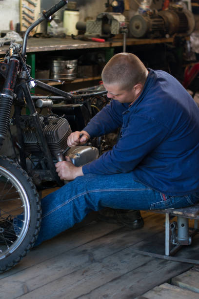 istock Man with tools repairing old motorcycle in workshop 979891498