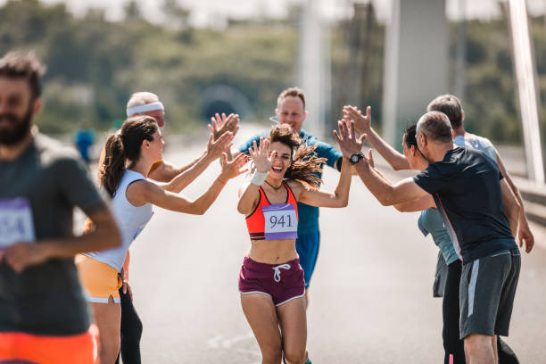 istock Happy athletes greeting their supporters while running a marathon on the road. 979896906
