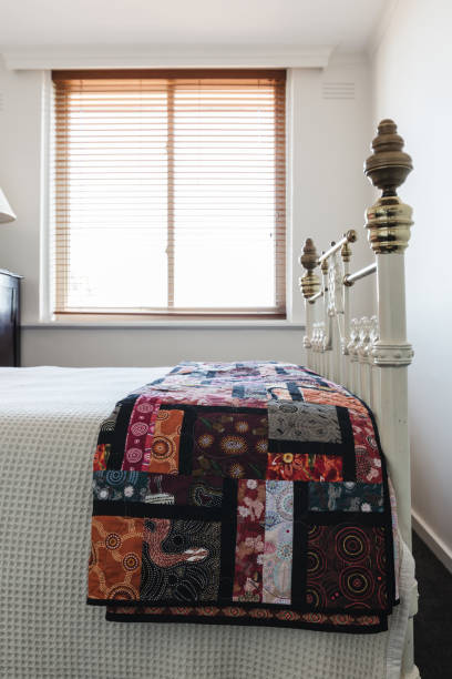 Patchword quilt details on a brass bed