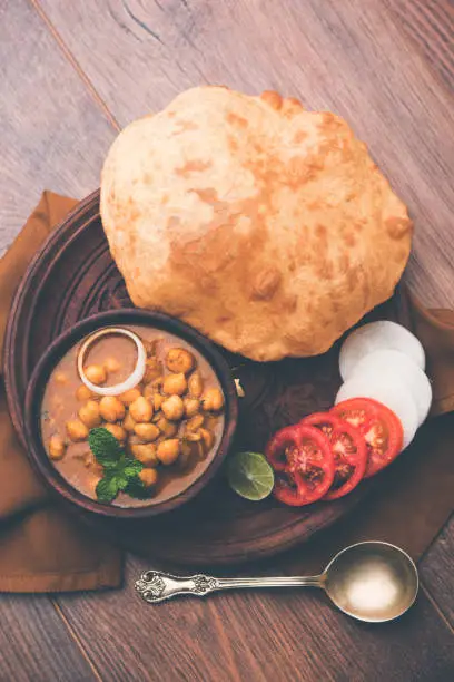 Chole Bhature or Chick pea curry and Fried  Puri served in terracotta crockery over white background. selective focus