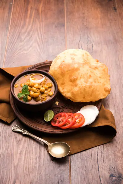 Chole Bhature or Chick pea curry and Fried  Puri served in terracotta crockery over white background. selective focus