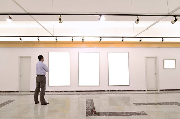 Man standing in a gallery looking at three blank displays
