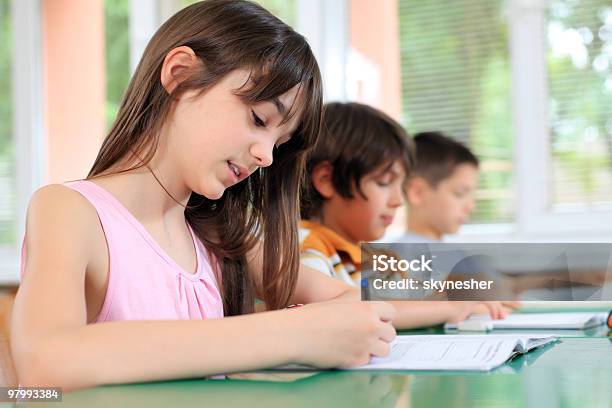 Los Escolares Escribiendo En El Cuaderno De En La Lección Foto de stock y más banco de imágenes de Niño de edad escolar