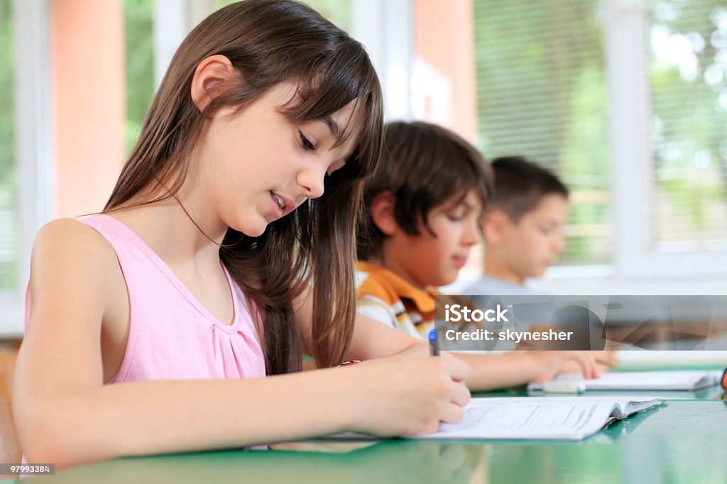 Schoolchildren pisania w notatniku na lekcji. - Zbiór zdjęć royalty-free (Dzieci w szkole)