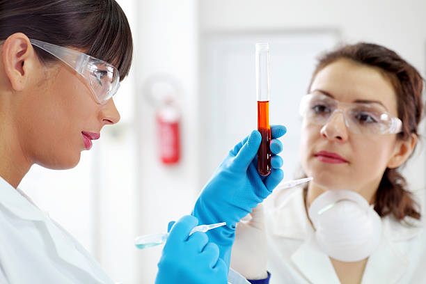 assistente di laboratorio look liquido rosso in provetta. - test tube biologist laboratory beaker foto e immagini stock