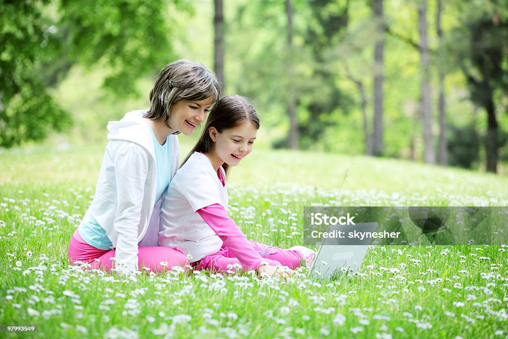 Mother and her daughter sitting with laptop outside.  Agricultural Field Stock Photo