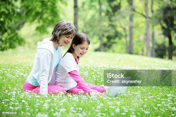 Mother And Her Daughter Sitting With Laptop Outside Stock Photo - Download Image Now