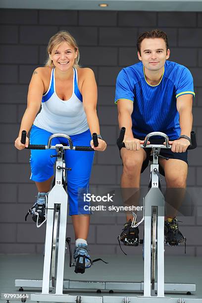 Man And Woman Exercising On Bicycles In A Gym Stockfoto en meer beelden van Sportschool - Sportschool, Fietsen, Fotografie