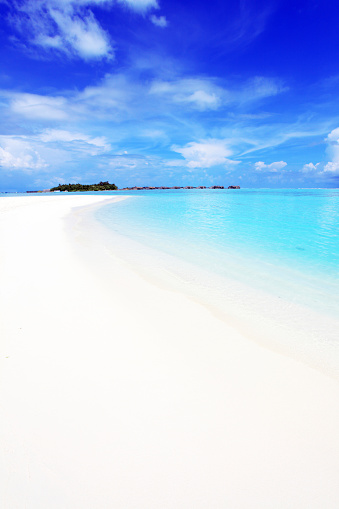 blinding white sand beach meeting the blue ocean waves and sky.