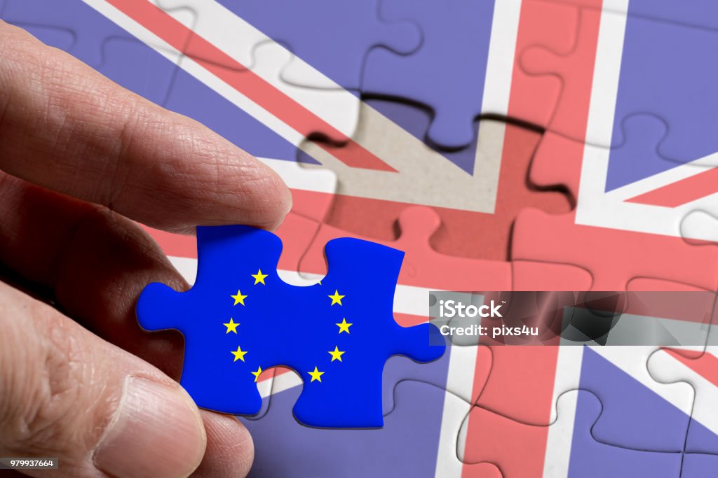 Mano que sostiene la pieza de rompecabezas con la bandera de la Unión Europea y Gran Bretaña. - Foto de stock de Agarrar libre de derechos