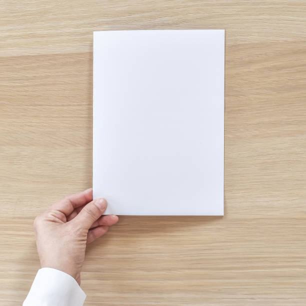 Mock up bi-fold brochure flyer pamphlet design A4 size half-folded (A5) paper layout space for template illustration mockup in businessman's hand, flat lay on wood table from top view