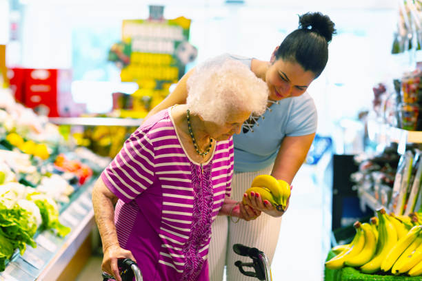 caregiver helping senior woman with shopping stock photo