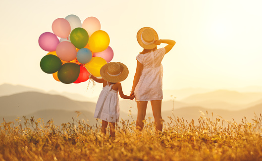 happy family mother and child daughter with balloons at sunset in summer