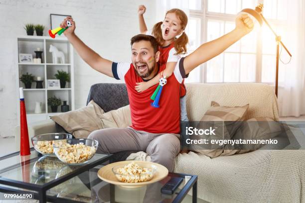 Family Of Fans Watching A Football Match On Tv At Home Stock Photo - Download Image Now
