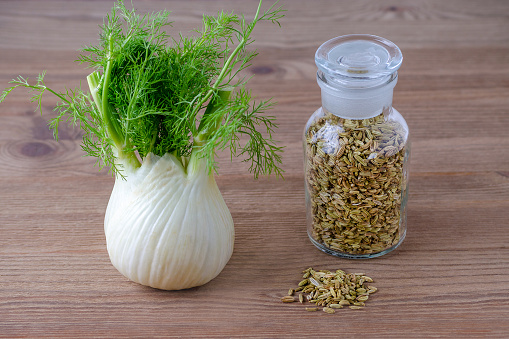 fennel bulb and seeds in a glass jar, on brown wooden background