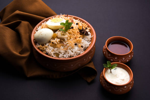 Egg Biryani - Basmati rice cooked with masala roasted eggs and spices and served with yogurt, selective focus