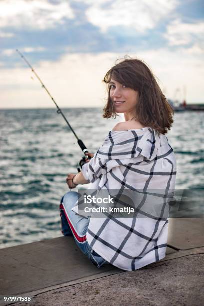 Smiling Young Woman Fishing On City Beach Stock Photo - Download