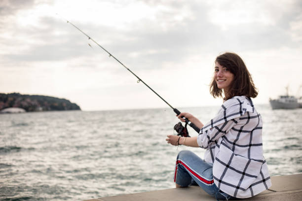 Smiling Young Woman Fishing on City Beach stock photo