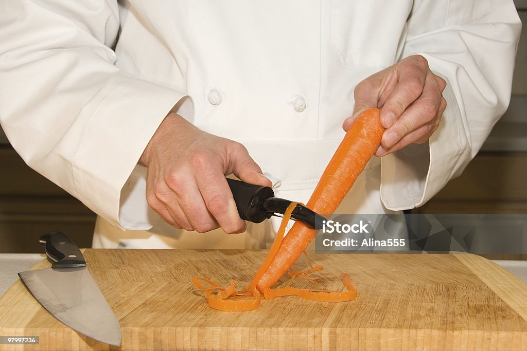 Manos de cook descamación una zanahoria en la cocina - Foto de stock de Adulto libre de derechos