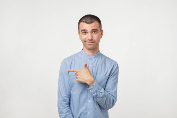 istock Young handsome man in blue shirt pointing away. 979978136