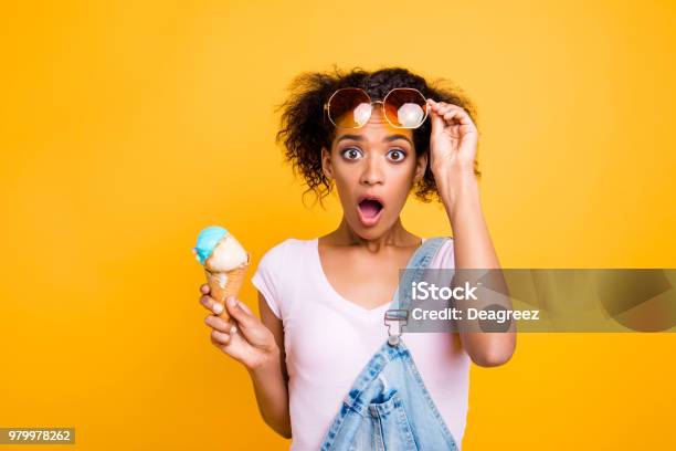 Wtf Portrait Of Shocked Frustrated Girl Looking Out Eyeglasses With Wide Open Eyes Mouth Having Ice Cream In Waffle Cone Isolated On Yellow Background Stock Photo - Download Image Now