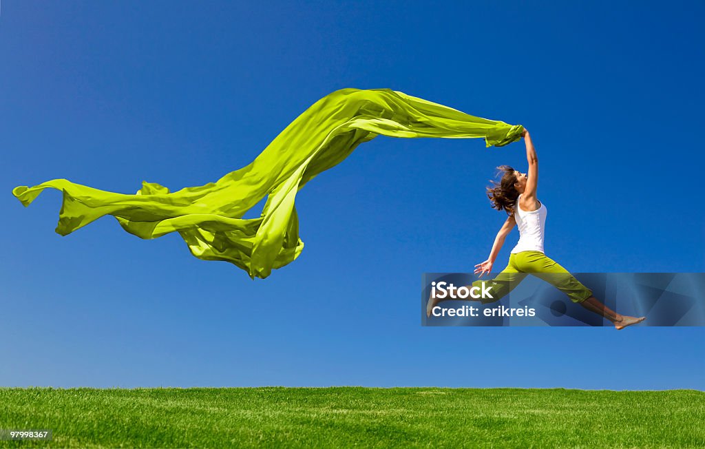 Frau springen auf der grünen Wiese mit einem farbigen Gewebe - Lizenzfrei Hochspringen Stock-Foto
