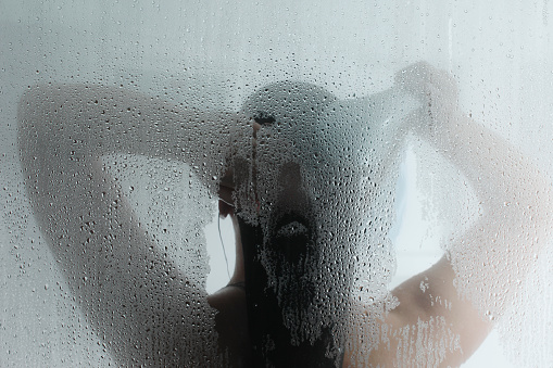 A female taking a hot steam shower.