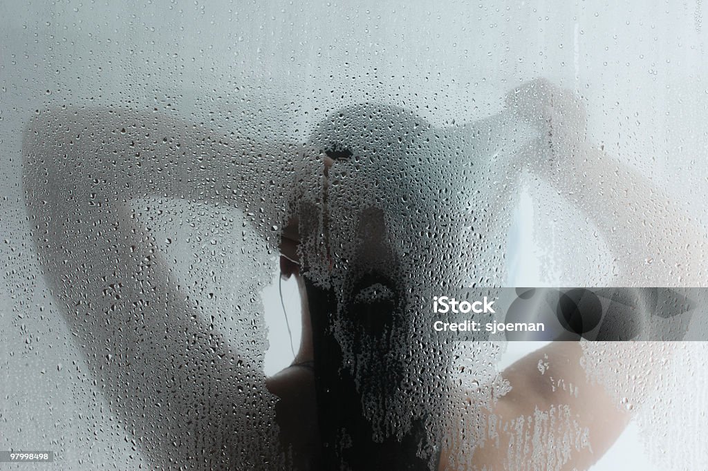 Silhouette of woman taking shower behind steamy door A female taking a hot steam shower. Shower Stock Photo