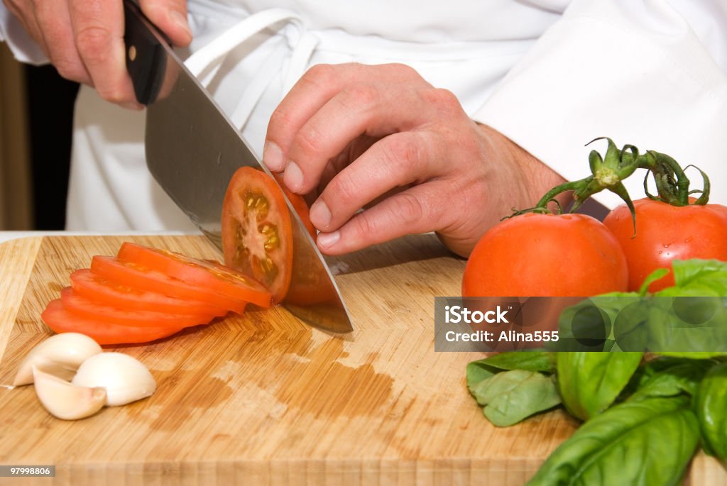 Mains du chef de cuisine coupe une tomate - Photo de Adulte libre de droits