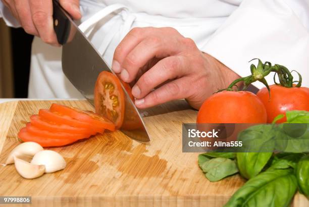 Photo libre de droit de Mains Du Chef De Cuisine Coupe Une Tomate banque d'images et plus d'images libres de droit de Adulte - Adulte, Ail - Légume à bulbe, Aliment cru