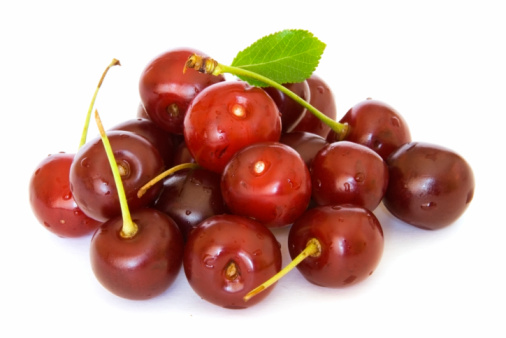 Ripe, Vibrant cherries tossed into mid air. Pure White background with depth of field.